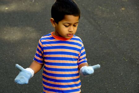An handsome Indian kid looking at the new mittensの写真素材