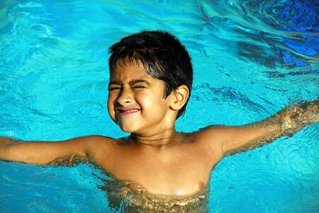 An young indian boy having fun smimming in the poolの写真素材