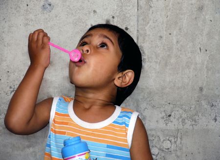 Young Indian kid having fun blowing bubblesの写真素材