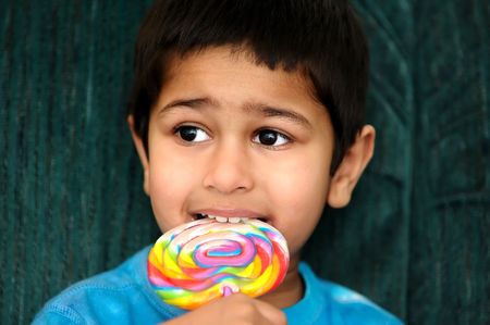An handsome Indian kid savoring his colorful candy