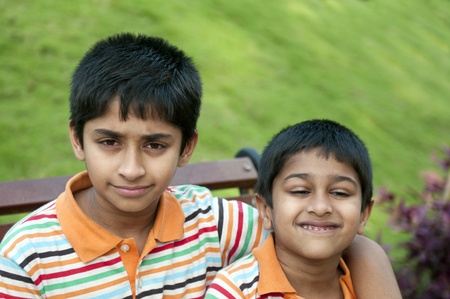 Two Indian brothers sitting happily at a local parkの写真素材