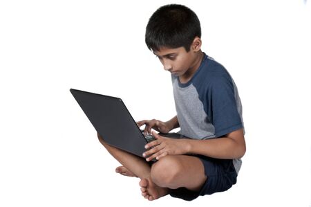 An handsome Indian kid having fun with laptopの写真素材