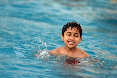 an handsome young indian kid swimming in the poolの写真素材