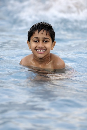 an handsome young indian kid swimming in the poolの写真素材