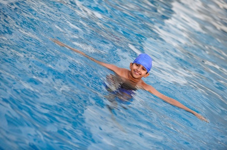 an handsome young indian kid swimming in the poolの写真素材