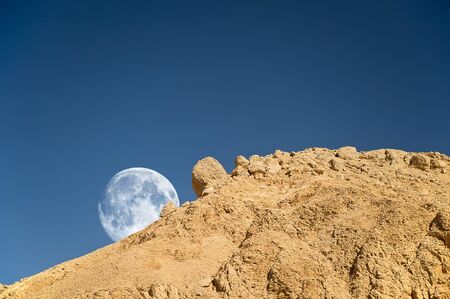 Full moon setting over the rocky desert in Egyptの写真素材