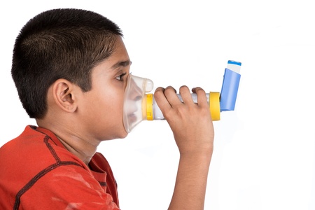 Close up image of a cute little boy using inhaler for asthma. White background の写真素材