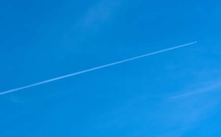 Diagonal airplane trace on a clear blue skyの写真素材