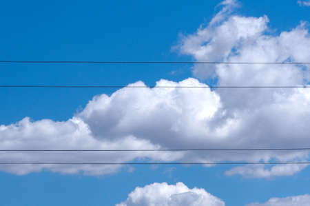 Four of electric wires against clear cloudy blue skyの写真素材