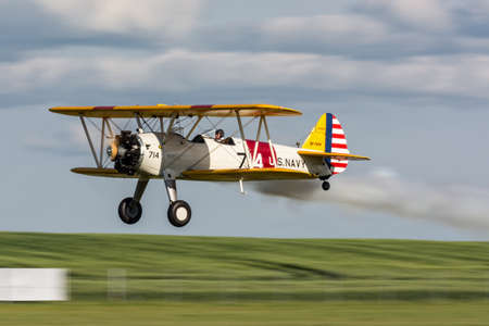 Vintage aircraft Boeing Stearman flying low with smoke on at I International Air Picnic