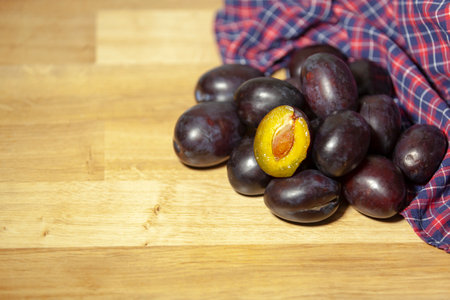A bunch of prunes on a wooden table. Fresh backyard harvest. Close-up, selective focus.の写真素材