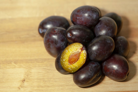 A bunch of prunes on a wooden table. Fresh backyard harvest. Close-up, selective focus.の写真素材