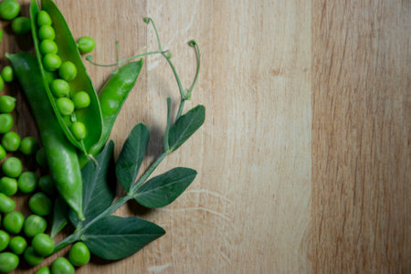 Fresh green peas. Several peas and an open pod on a wooden background. Top view, copy space.の写真素材
