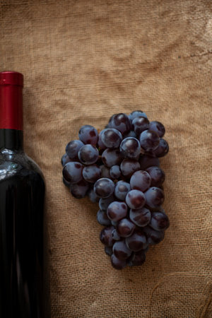 Moldovan wine. Bunch of grapes and a bottle of red wine on burlap. View from above. Copy space.の写真素材