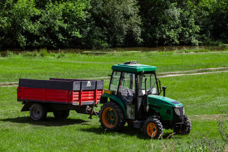 Compact tractor on a rural lawn with forest and river in the backgroundの写真素材