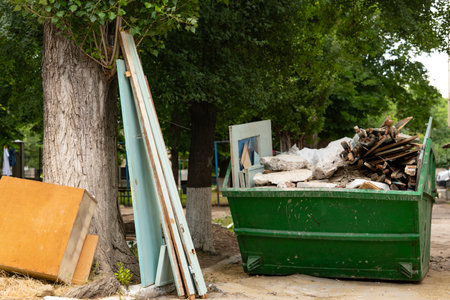 Industrial waste container filled with construction waste, located in the block's yard. Horizontal...