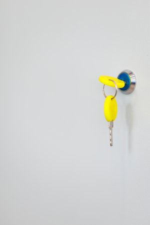 Yellow-tag key in lock. Vertical photo of key in modern lock indoors with copy space for real estate...