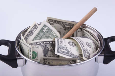 Silver cooking pot full of dollar banknotes with wooden spoon