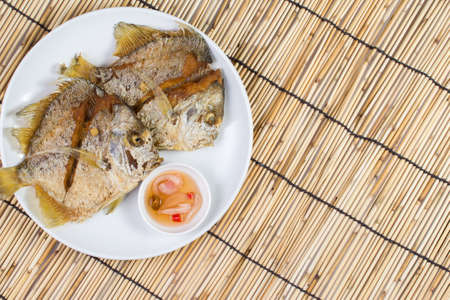 two fried fish and sauce on a white plateの写真素材