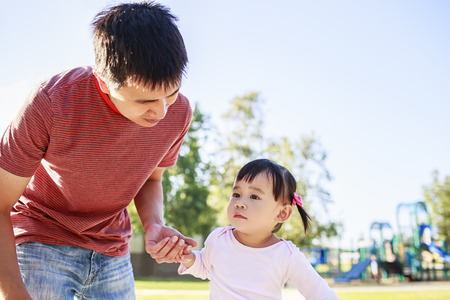 Toddler girl playing outdoor with fatherの写真素材