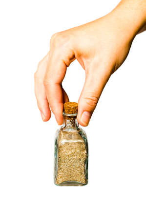 Pretty female hand show a small glass bottle with beach sand in it is interiorの写真素材