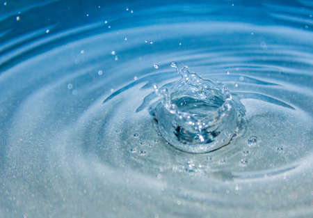 Water splash with small drops in blue backgroundの写真素材