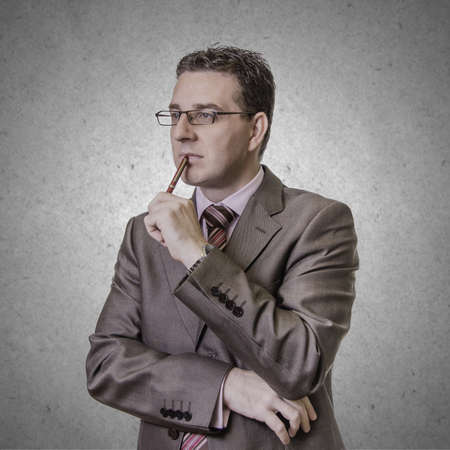 Portrait of thoughtful young businessman with pen in his hand, isolated on white backgroundの写真素材