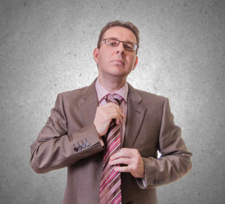 Portrait of thoughtful young businessman putting his stripes tie, isolated on white backgroundの写真素材