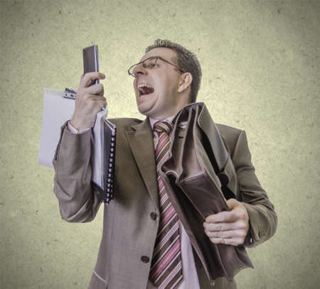 Portrait of busy and angry businessman screaming at smartphone, isolated on white backgroundの写真素材
