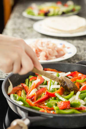 Closeup of female cooking vegetables and chicken for a mexican food in a black panの写真素材
