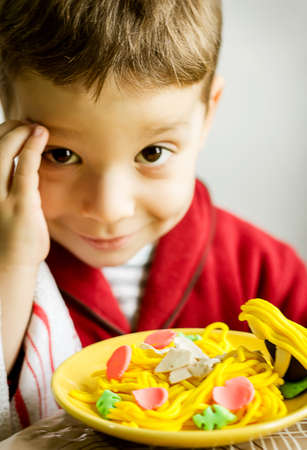 Portrait of cute child posing with his original spaghetti dish, made with colorful plasticine