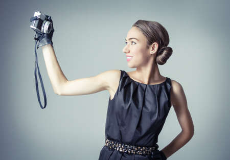 Fashion portrait of beautiful young girl in classic vintage style with an analogue photo camera