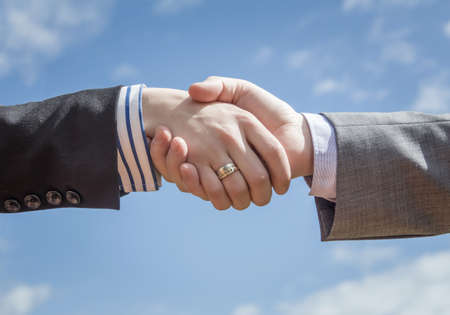 Closeup of a business handshake over blue sky backgroundの写真素材