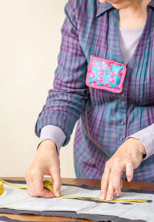 Woman dressmaker measuring tailor pattern for a suit on the table