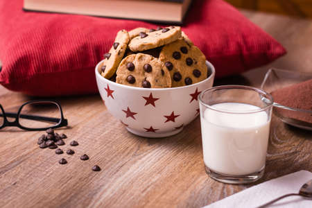 Closeup of chocolate chip cookies on stars bowl and milk glass over a wooden backgroundの写真素材