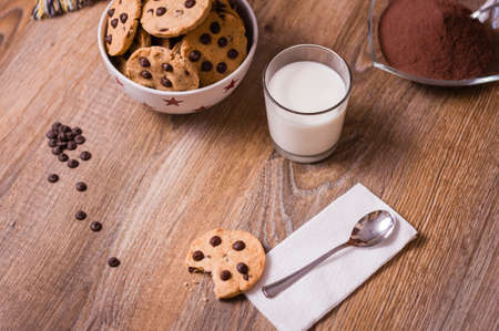Closeup of chocolate chip cookies on stars bowl and milk glass over a wooden backgroundの写真素材