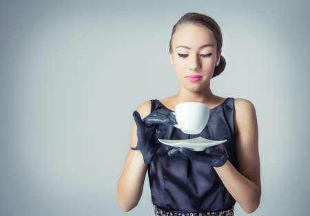 Fashion portrait of beautiful young girl with a coffee cup in classic vintage styleの写真素材