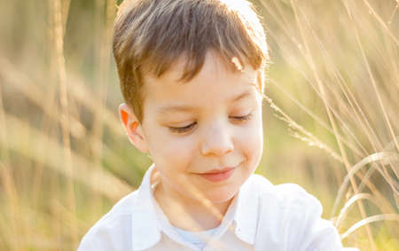 Happy cute kid in a field playing with natural spikes at summer sunset  Soft colors edition の写真素材