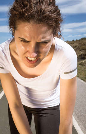 Portrait of tired runner girl sweating after running hard in a outdoor training on sunny day