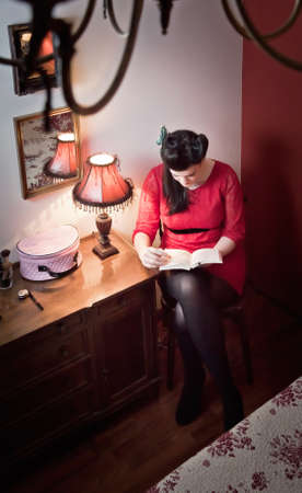 Portrait of beautiful fashion young girl with white makeup and wearing retro red dress reading a book  Classic vintage style concept の写真素材
