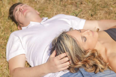 Beautiful love couple lying on the grass in a summer dayの写真素材