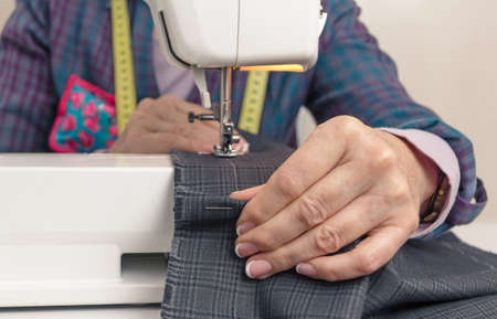 Closeup of seamstress hands working with clothing item on a sewing machine  Focus in the foreground...