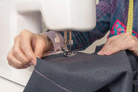 Closeup of seamstress hands working with clothing item on a sewing machine