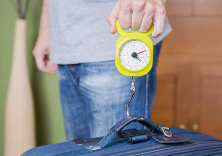Man checking hand luggage weight using a steelyard balance by low cost airlines restrictionsの写真素材