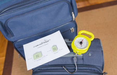 Low cost airlines luggage restrictions and baggage ready to weight with a steelyard balance on the backgroundの写真素材