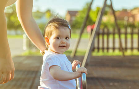 Adorable little baby girl playing over a seesaw swing on the parkの写真素材