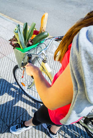 Closeup of sportive woman with groceries in a basket bike on a sunny summer dayの写真素材