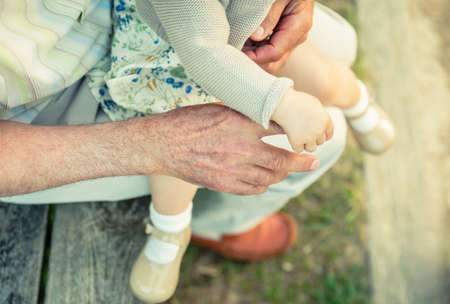 Baby girl holding finger of senior man hand. Two different generations concept.の写真素材