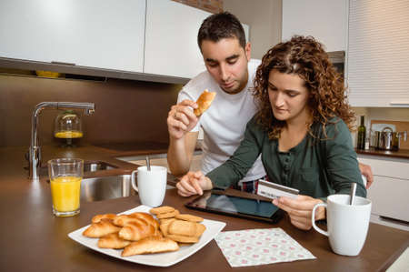 Portrait of young couple with electronic tablet and credit card buying on internet