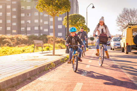Happy family with a child riding bicycles by the city on a sunny winter dayの写真素材